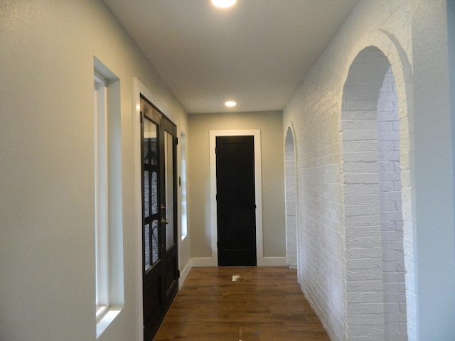 hallway featuring brick wall, baseboards, wood finished floors, and recessed lighting