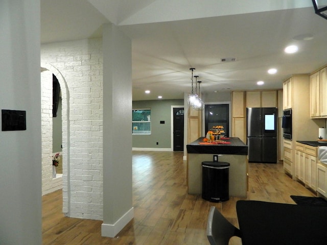 kitchen with light wood-type flooring, pendant lighting, a center island, and black appliances