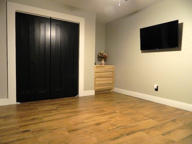 unfurnished bedroom featuring a closet, baseboards, and wood finished floors