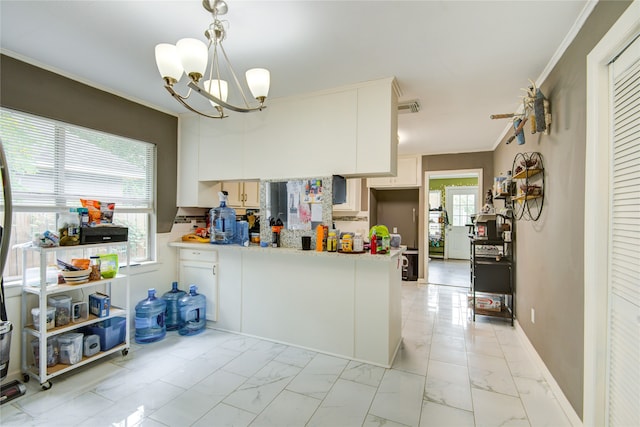 kitchen featuring kitchen peninsula, ornamental molding, decorative light fixtures, a notable chandelier, and white cabinets