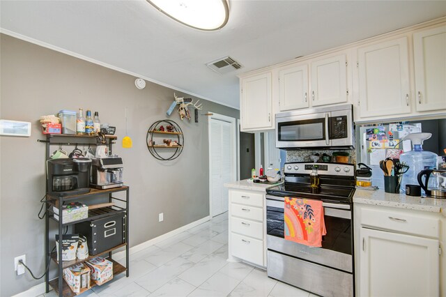 kitchen with light stone countertops, appliances with stainless steel finishes, white cabinetry, and ornamental molding