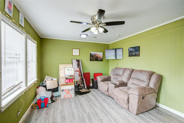 living room with ceiling fan, ornamental molding, a wealth of natural light, and light hardwood / wood-style flooring