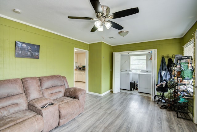 living room with light hardwood / wood-style floors, ceiling fan, ornamental molding, and washing machine and clothes dryer