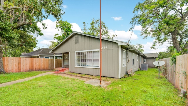 back of house featuring central air condition unit and a lawn