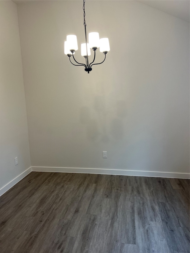 spare room with an inviting chandelier, lofted ceiling, and dark wood-type flooring