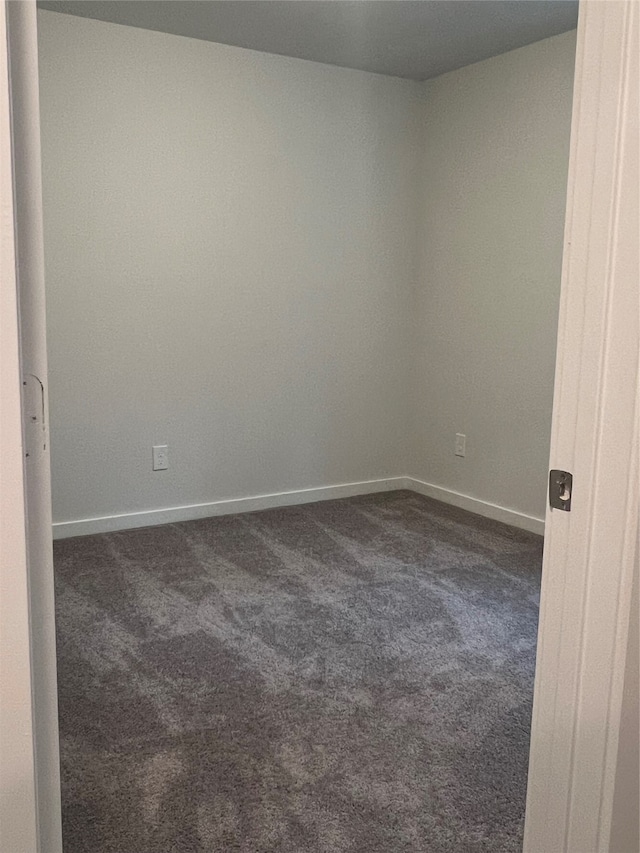 unfurnished room with dark carpet