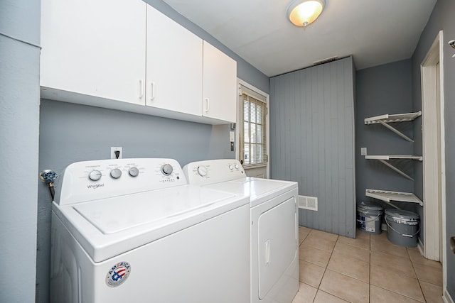 laundry area with light tile patterned floors, separate washer and dryer, and cabinets