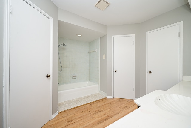 bathroom featuring vanity, hardwood / wood-style floors, and tiled shower / bath combo