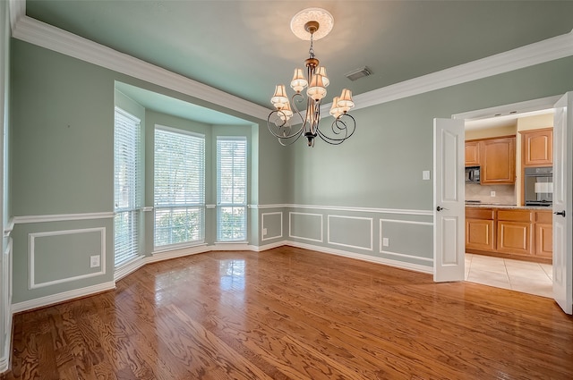 unfurnished dining area with crown molding, light hardwood / wood-style floors, and a notable chandelier