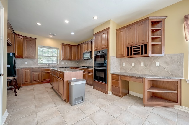 kitchen featuring black appliances, decorative backsplash, a center island, and sink