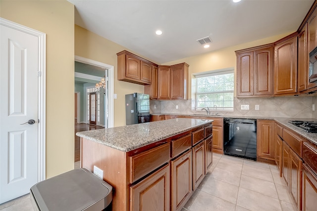 kitchen featuring backsplash, light stone counters, light tile patterned floors, dishwasher, and a center island