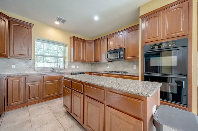 kitchen with light stone countertops, sink, decorative backsplash, light tile patterned floors, and black appliances