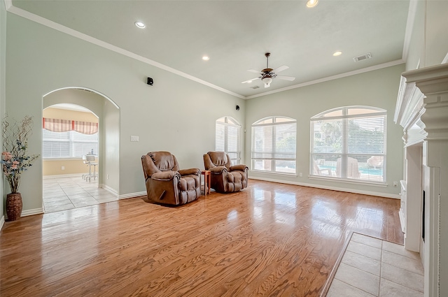 living area featuring light wood-type flooring, crown molding, ceiling fan, and a healthy amount of sunlight