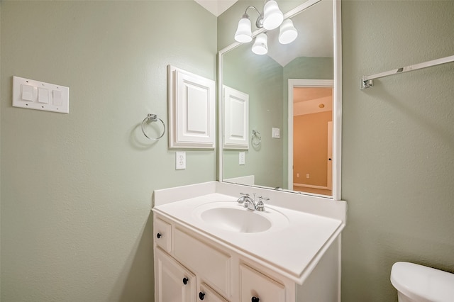 bathroom featuring toilet, vanity, vaulted ceiling, and a notable chandelier