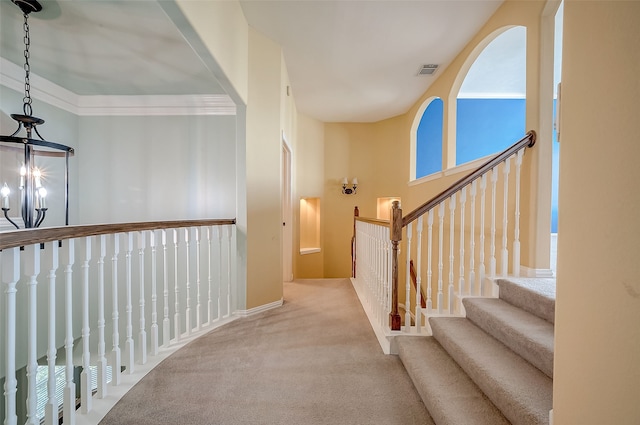 corridor with a chandelier, light carpet, and crown molding