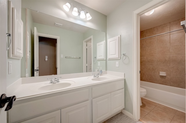 full bathroom featuring tile patterned flooring, vanity, toilet, and tiled shower / bath