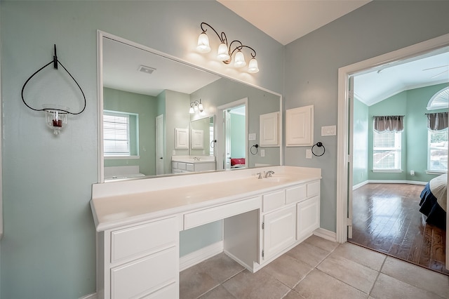 bathroom featuring tile patterned flooring, vanity, and vaulted ceiling