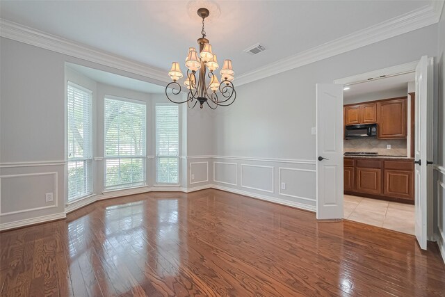 20807 Twisted Leaf Dr, Cypress, TX 77433 - empty room featuring a chandelier, crown molding, a decorative wall, wainscoting, and light wood-style flooring