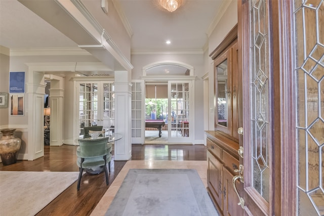 entrance foyer with wood-type flooring, decorative columns, crown molding, and french doors