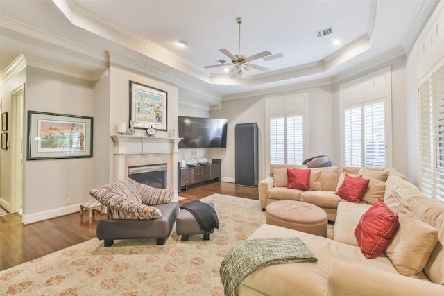 living room featuring crown molding, a fireplace, dark wood-type flooring, and ceiling fan