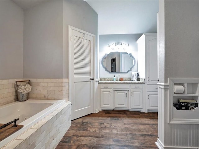 bathroom with a relaxing tiled tub, vanity, and hardwood / wood-style flooring