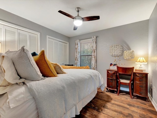 bedroom with ceiling fan, multiple closets, and hardwood / wood-style flooring