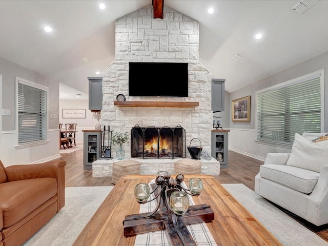 living room featuring light hardwood / wood-style floors, lofted ceiling with beams, and a fireplace