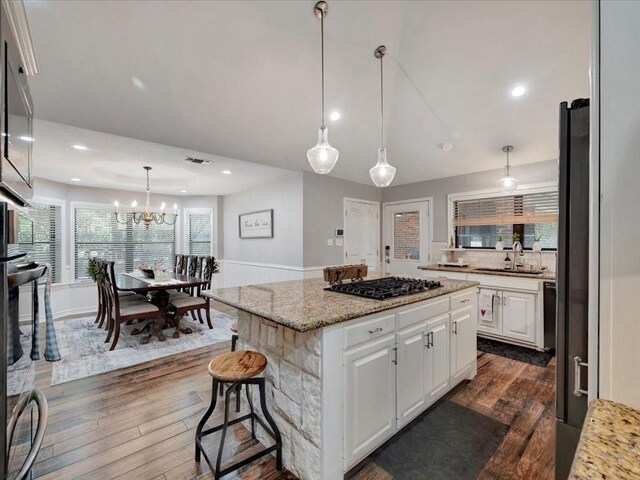 kitchen with white cabinets, sink, a center island, gas cooktop, and dark hardwood / wood-style flooring