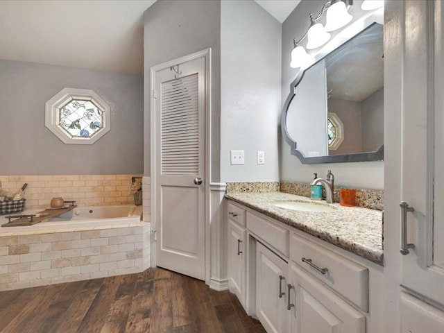 bathroom with tiled bath, vanity, and hardwood / wood-style flooring