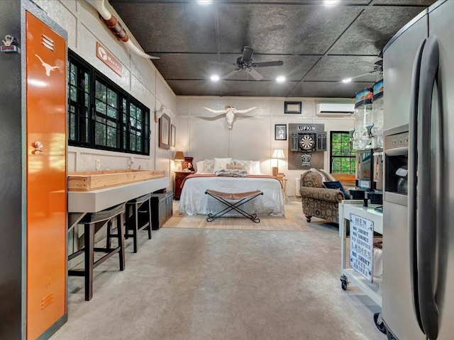 bedroom featuring stainless steel fridge, ceiling fan, concrete flooring, and a wall mounted air conditioner