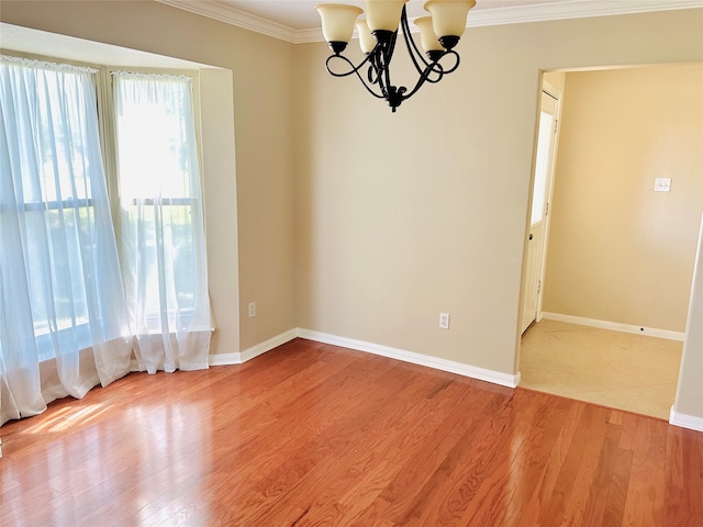 empty room featuring a notable chandelier, crown molding, and light hardwood / wood-style floors