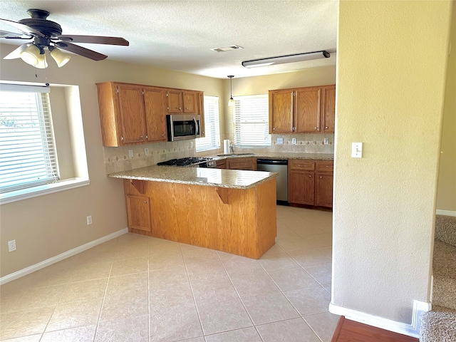 kitchen featuring ceiling fan, stainless steel appliances, kitchen peninsula, and a healthy amount of sunlight