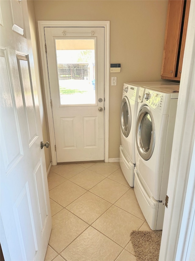 laundry room featuring light tile patterned floors, washer and dryer, and cabinets