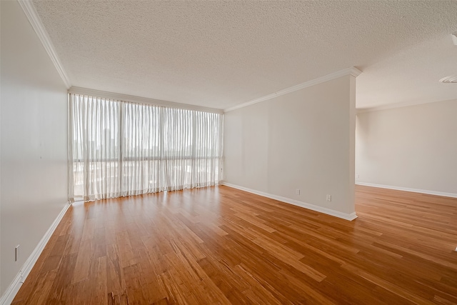 spare room with wood-type flooring, a textured ceiling, and crown molding