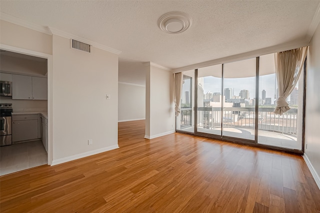 interior space with a textured ceiling, light hardwood / wood-style flooring, and ornamental molding