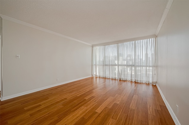 spare room featuring a textured ceiling, wood-type flooring, and crown molding