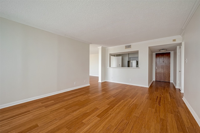 spare room with light hardwood / wood-style flooring, a textured ceiling, and crown molding