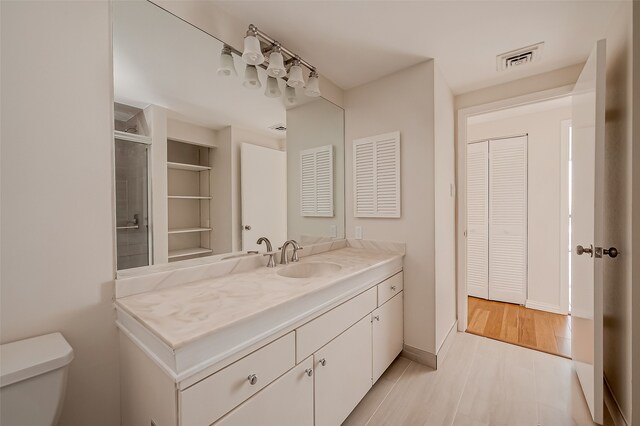 bathroom with walk in shower, vanity, toilet, and wood-type flooring