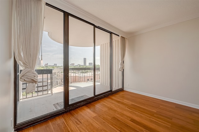 spare room featuring a textured ceiling, ornamental molding, and hardwood / wood-style flooring