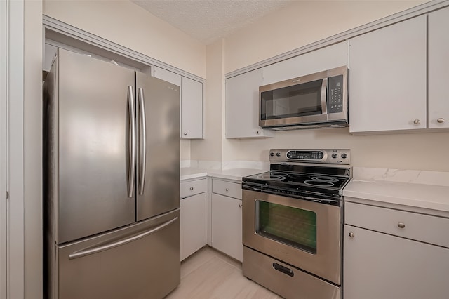 kitchen with white cabinets, a textured ceiling, and appliances with stainless steel finishes