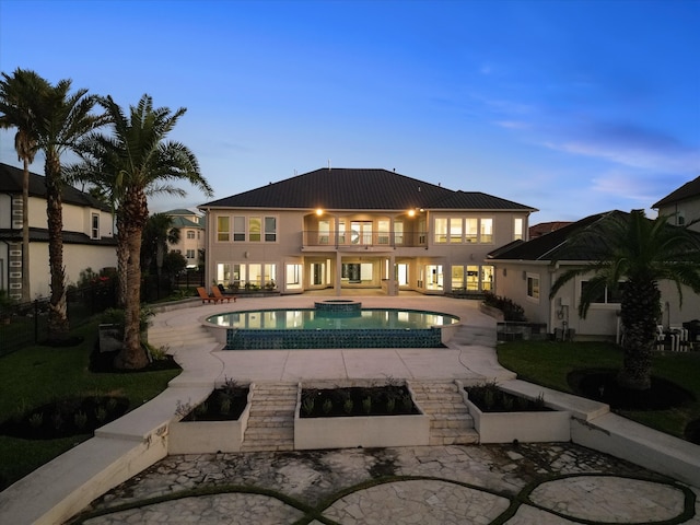 pool at dusk featuring an in ground hot tub and a patio area