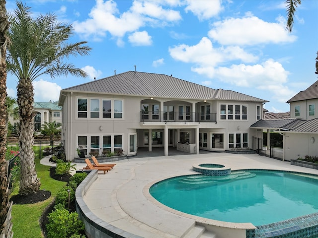 rear view of house featuring a balcony, a patio area, and a pool with hot tub