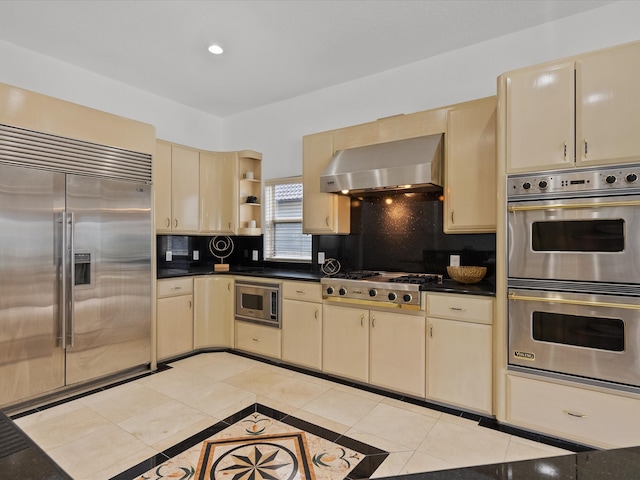 kitchen featuring backsplash, light tile patterned flooring, exhaust hood, and built in appliances