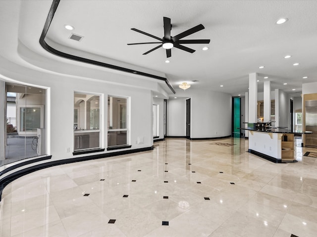 unfurnished living room featuring ceiling fan, a textured ceiling, and a healthy amount of sunlight