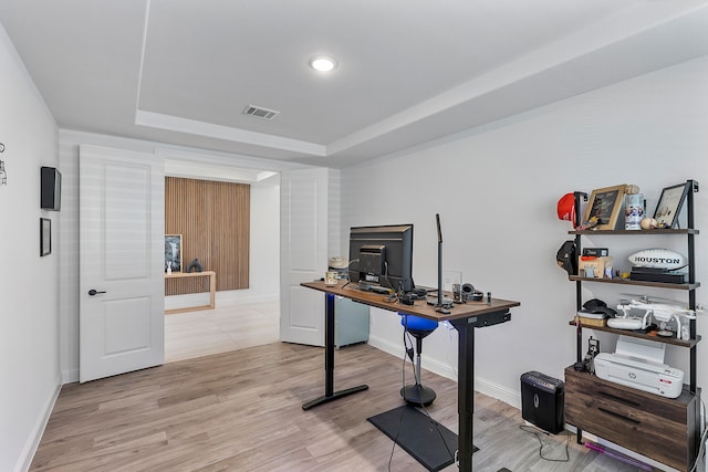 office space featuring a raised ceiling and light hardwood / wood-style flooring