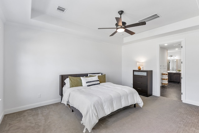 bedroom featuring ceiling fan, a raised ceiling, carpet floors, and ensuite bath