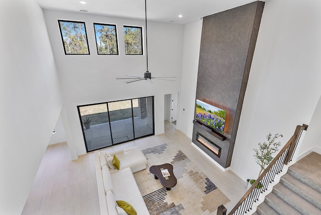 living room featuring ceiling fan, a fireplace, and a high ceiling