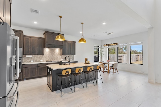 11915 Parsifal Creek Rd, Humble, TX 77346 - kitchen featuring stainless steel appliances, a kitchen breakfast bar, a center island with sink, backsplash, and light countertops