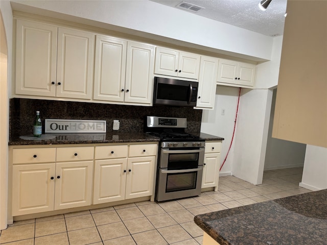 kitchen with appliances with stainless steel finishes, backsplash, a textured ceiling, and light tile patterned floors