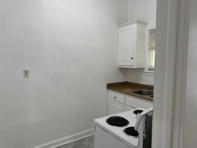 kitchen with light tile patterned flooring, white range with electric cooktop, sink, and white cabinets